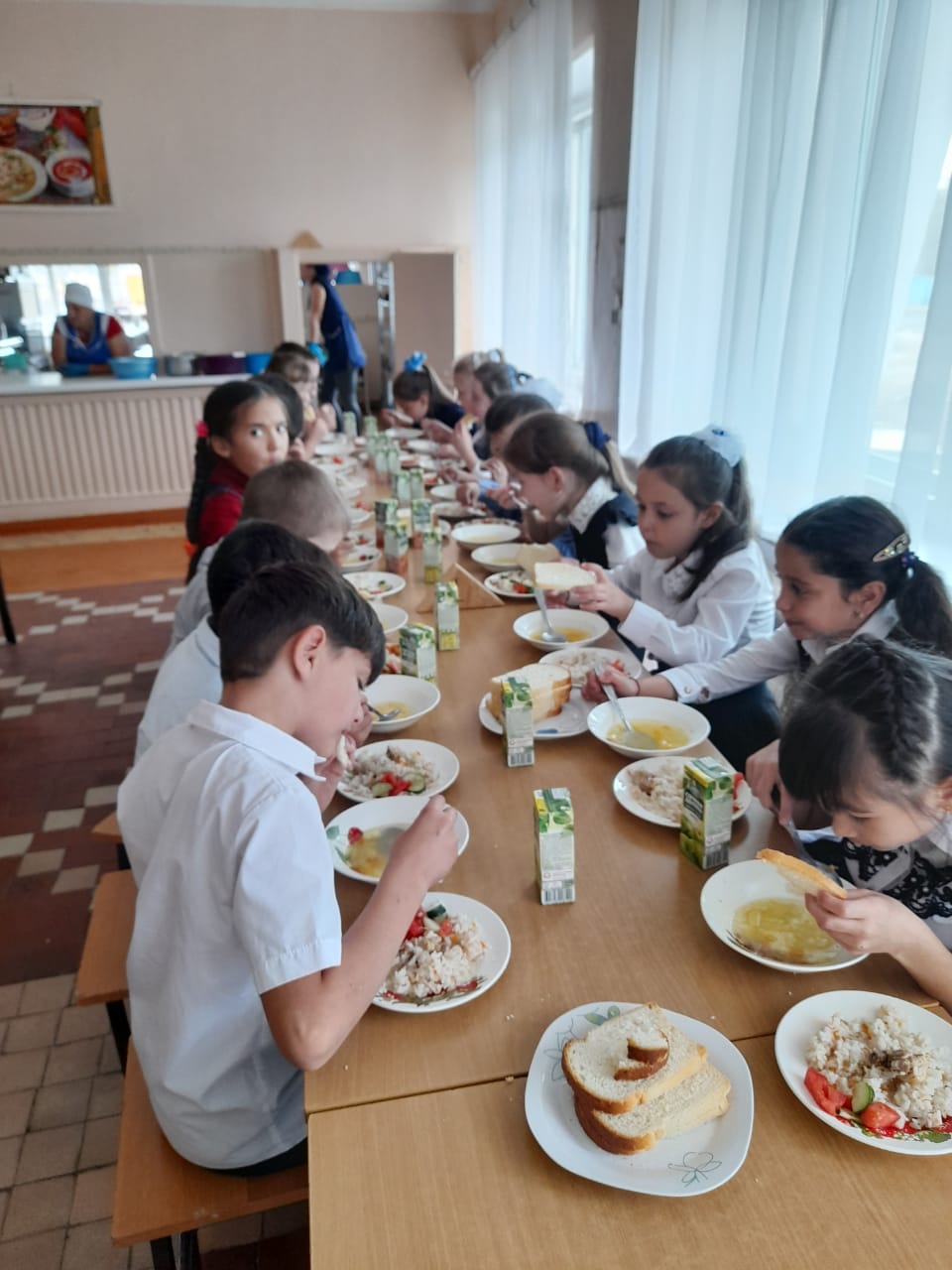 Учащиеся начальной школы за обеденным столом.